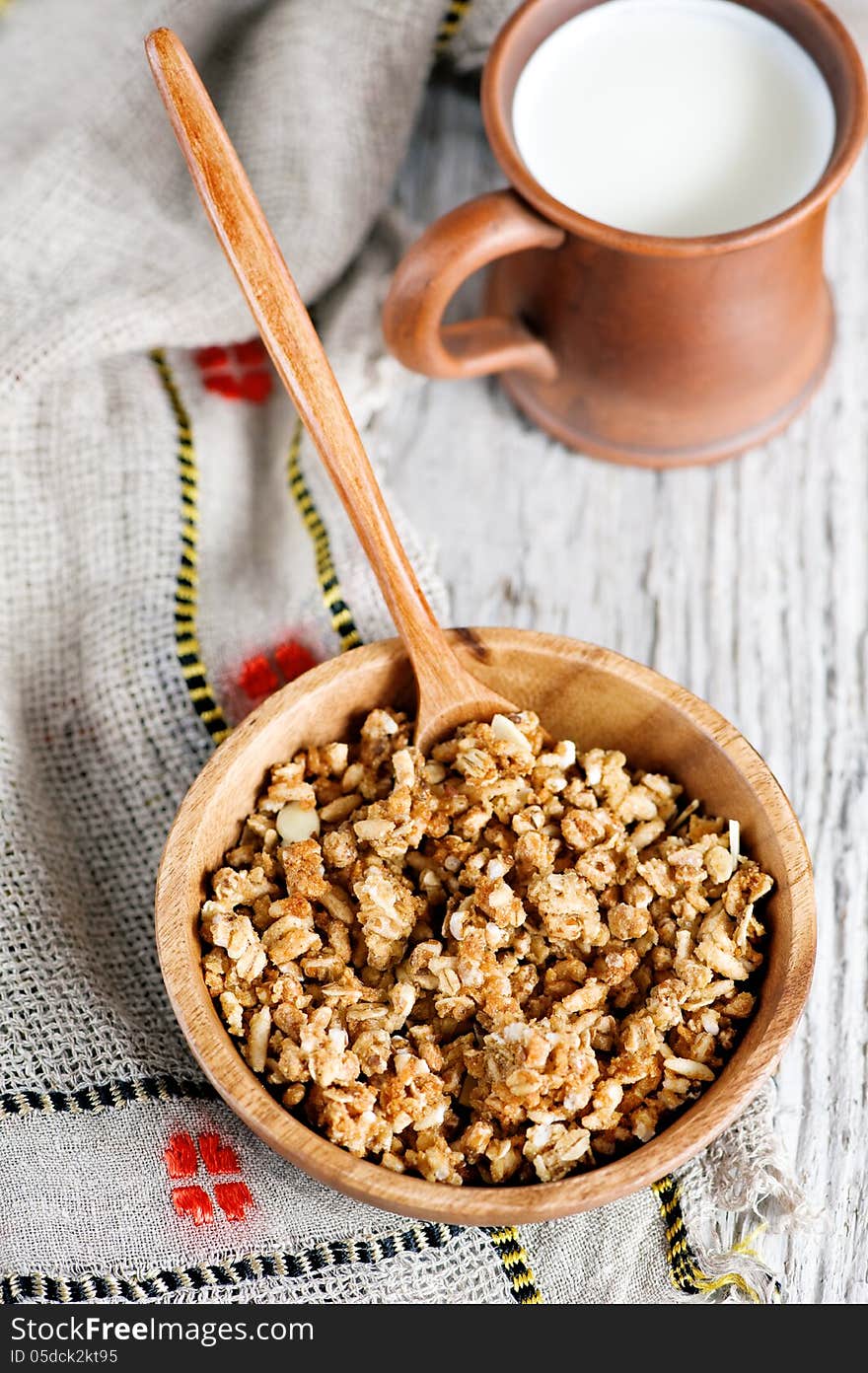 Muesli in wooden plate and milk in clay mug