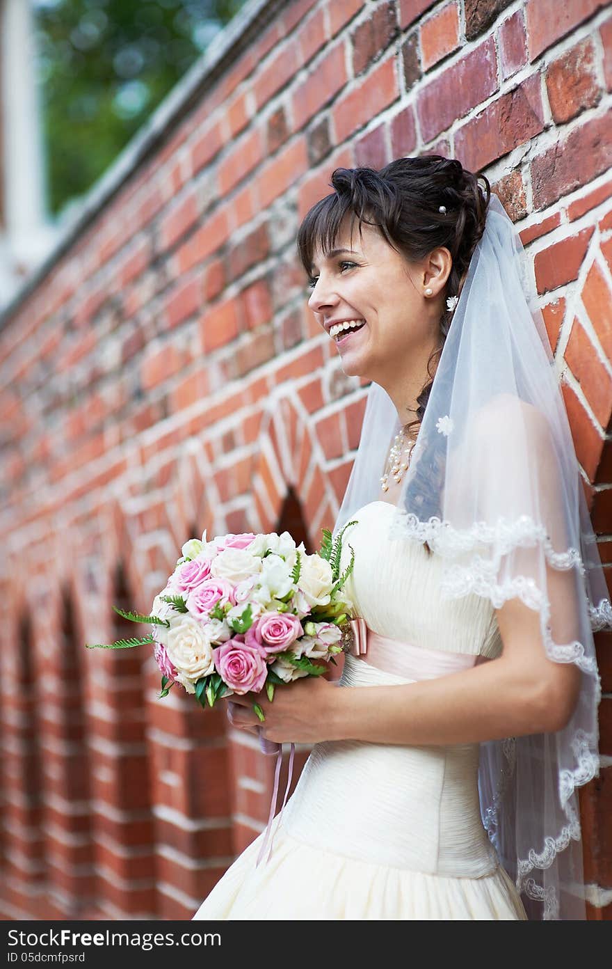 Happy bride near ancient wall in wedding walk