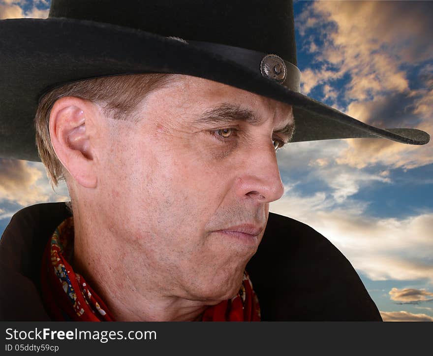 Profile of handsome serious man wearing a black cowboy hat and red bandana against beautiful sunset. Profile of handsome serious man wearing a black cowboy hat and red bandana against beautiful sunset