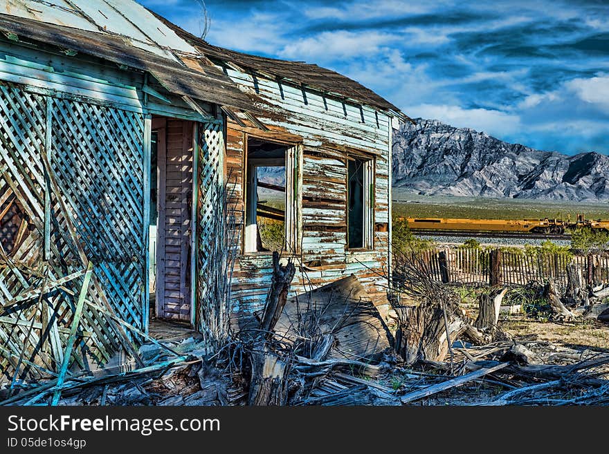 Abanonded tourquoise house in Mojave National Preserve with old picket fence train tracks and dramatic mountains in the background. Abanonded tourquoise house in Mojave National Preserve with old picket fence train tracks and dramatic mountains in the background