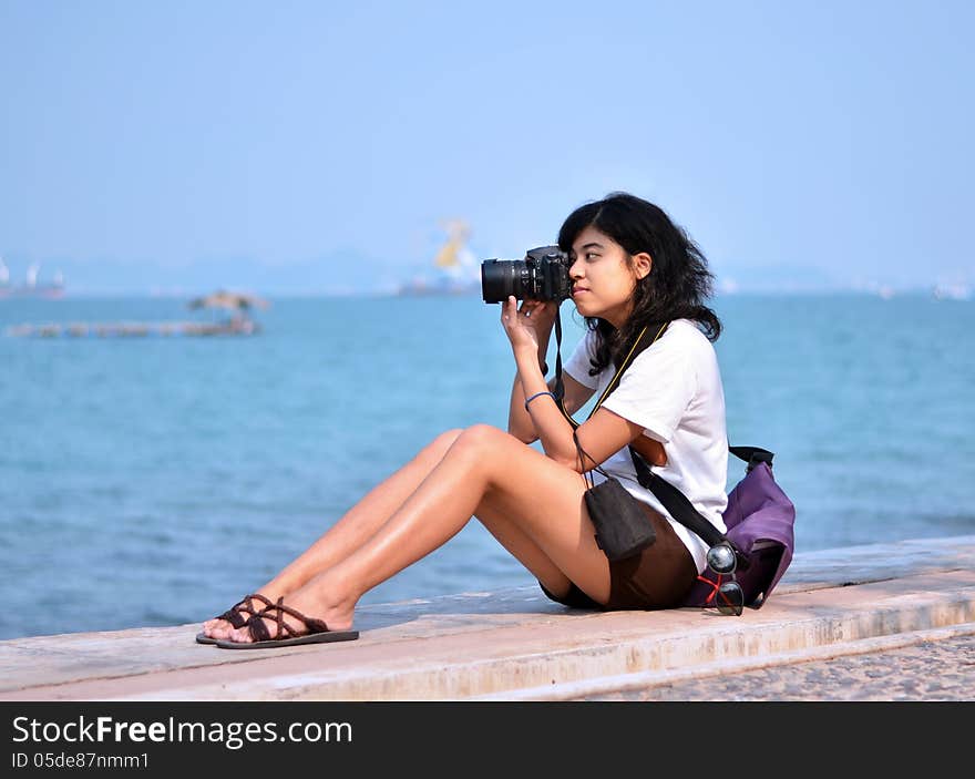 Beautiful young female photographer taking pictures on beach