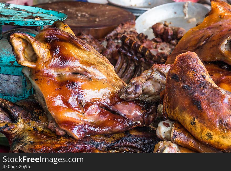 Detail of street food market with the head of a roasted pork in bad hygienic conditions.