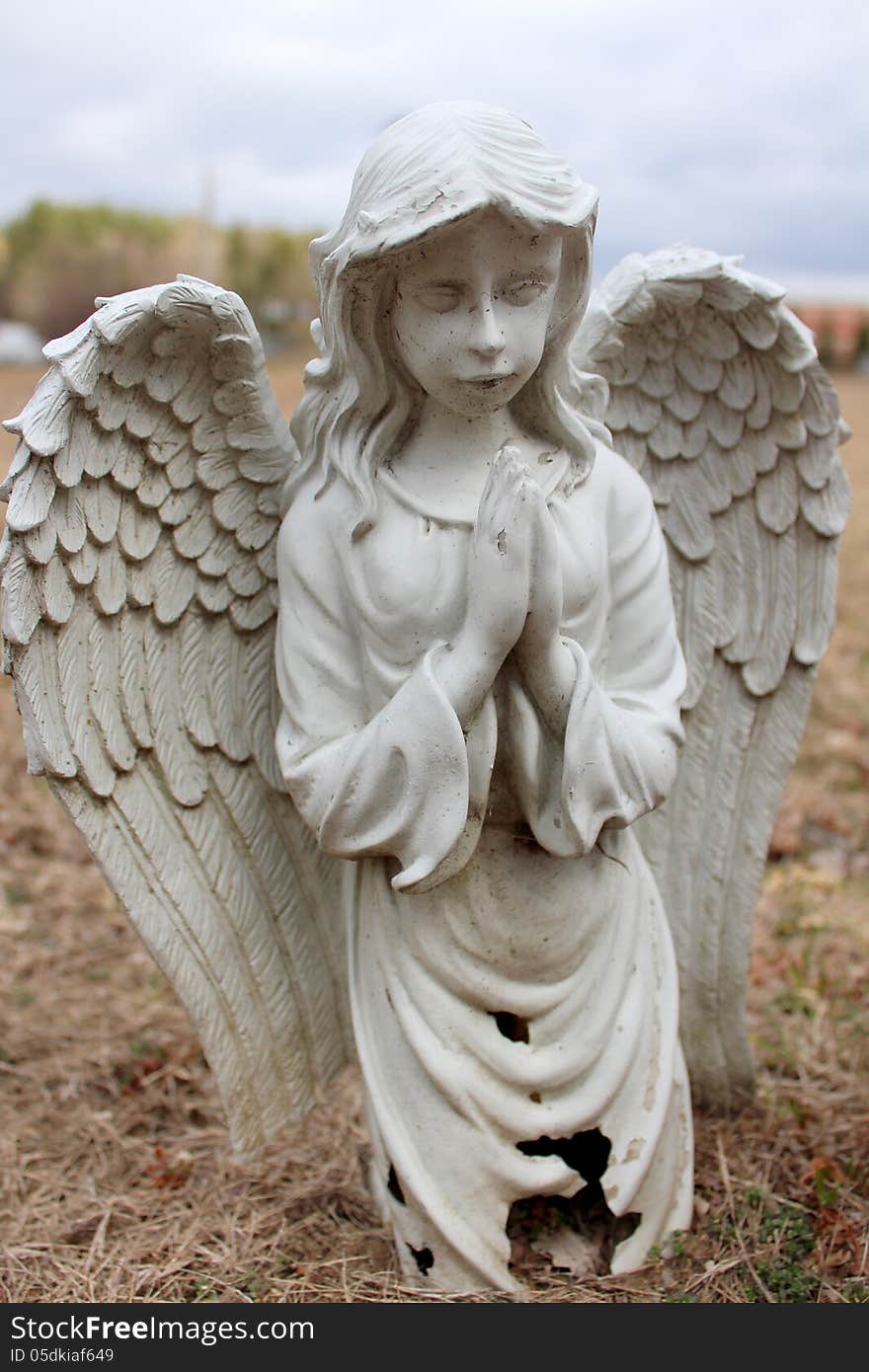 Old stone prayerful angel at graveside