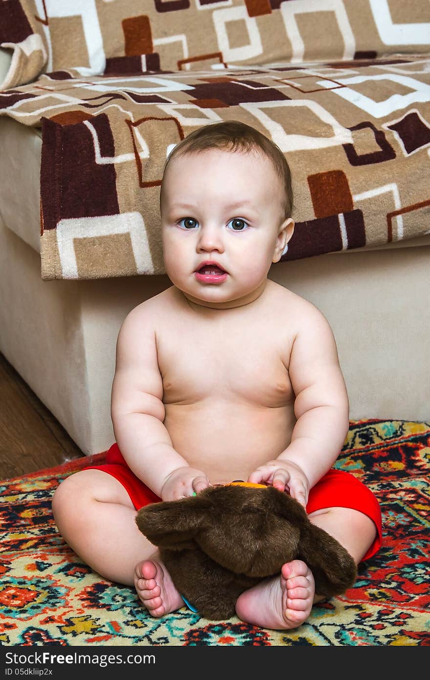 10 month child sitting with toy and looking ahead