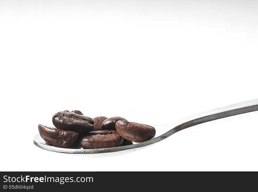 Coffee beans on a spoon isolated on white