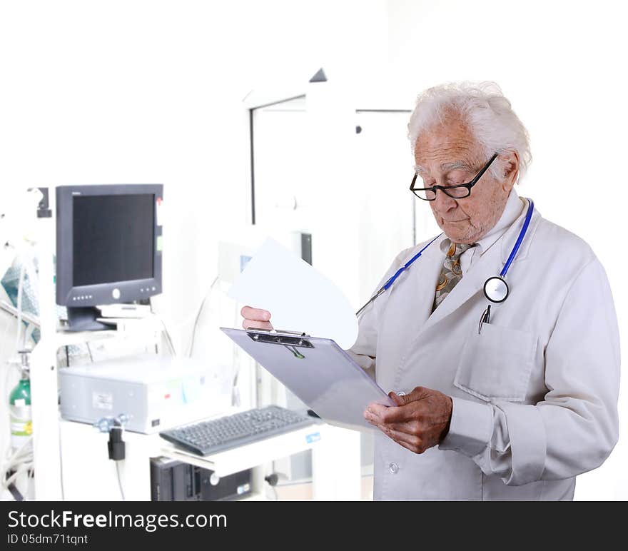 Senior doctor looking at a paper on a clipboard with a pulmonary function lab blurred in the back ground. Senior doctor looking at a paper on a clipboard with a pulmonary function lab blurred in the back ground.