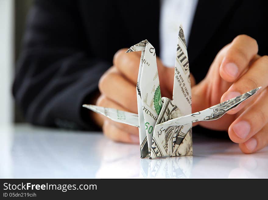 Business man hand holding origami paper cranes, money concept