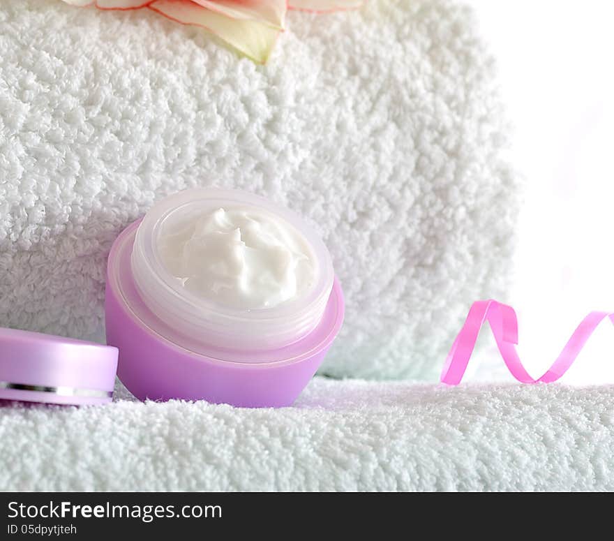 Cosmetic cream on white towels with amaryllis flower on white