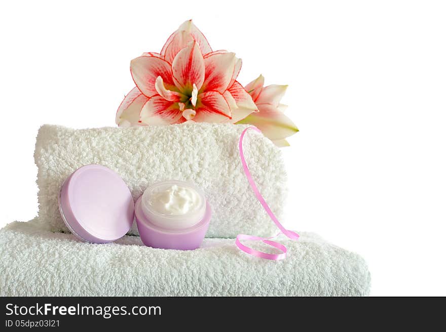 Cosmetic cream on white towels with amaryllis flower on white