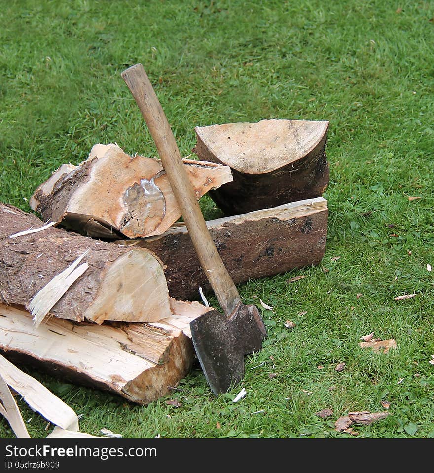 A Hand Axe Next to a Pile of Freshly Chopped Logs. A Hand Axe Next to a Pile of Freshly Chopped Logs.