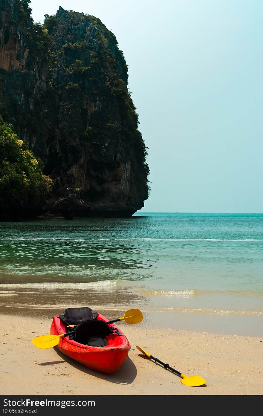 Tropical beach landscape with red canoe boat at ocean gulf under blue sky. Pranang cave beach, Railay, Krabi, Thailand