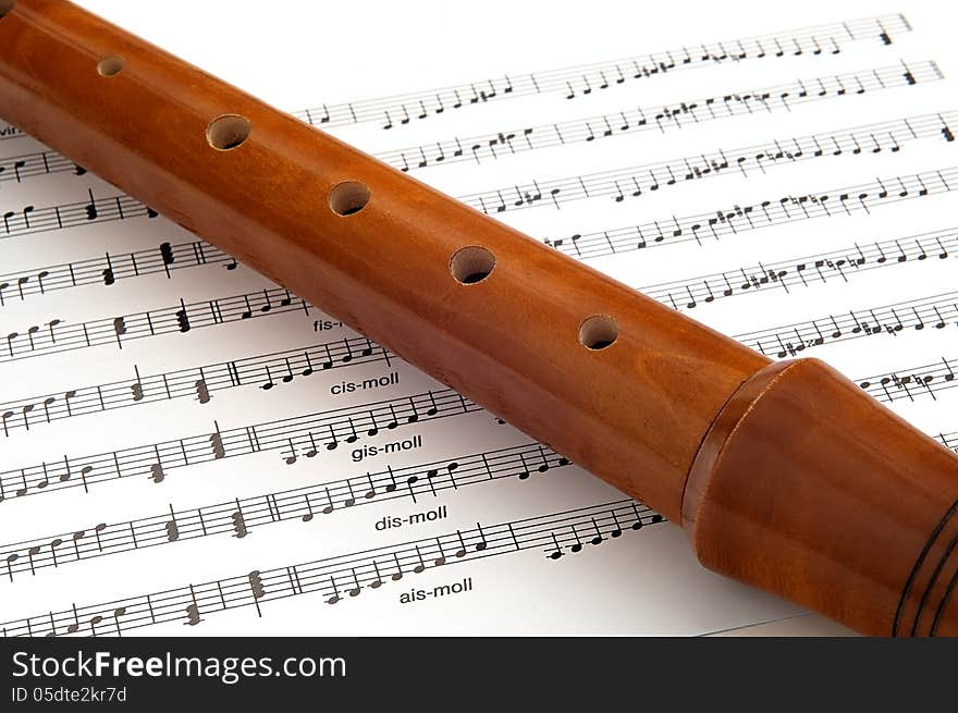 Wooden flute lying on musical notation. Wooden flute lying on musical notation