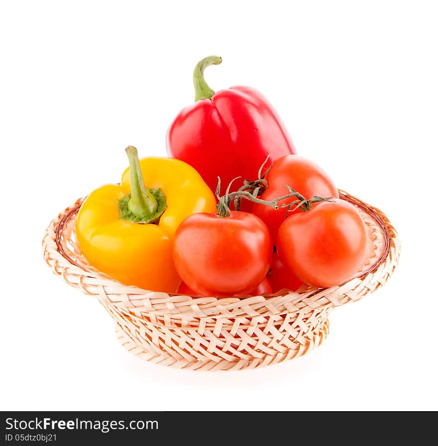 Tomatoes and peppers in a wicker basket on a white background