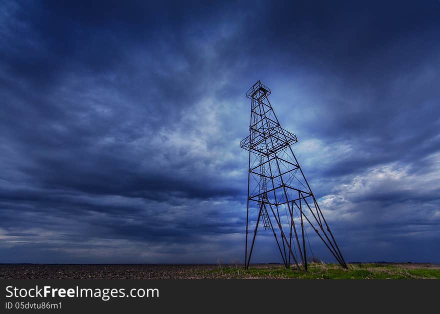 Oil and gas rig structure profiled on ominous stormy sky in active oilfield in Europe. Oil and gas rig structure profiled on ominous stormy sky in active oilfield in Europe