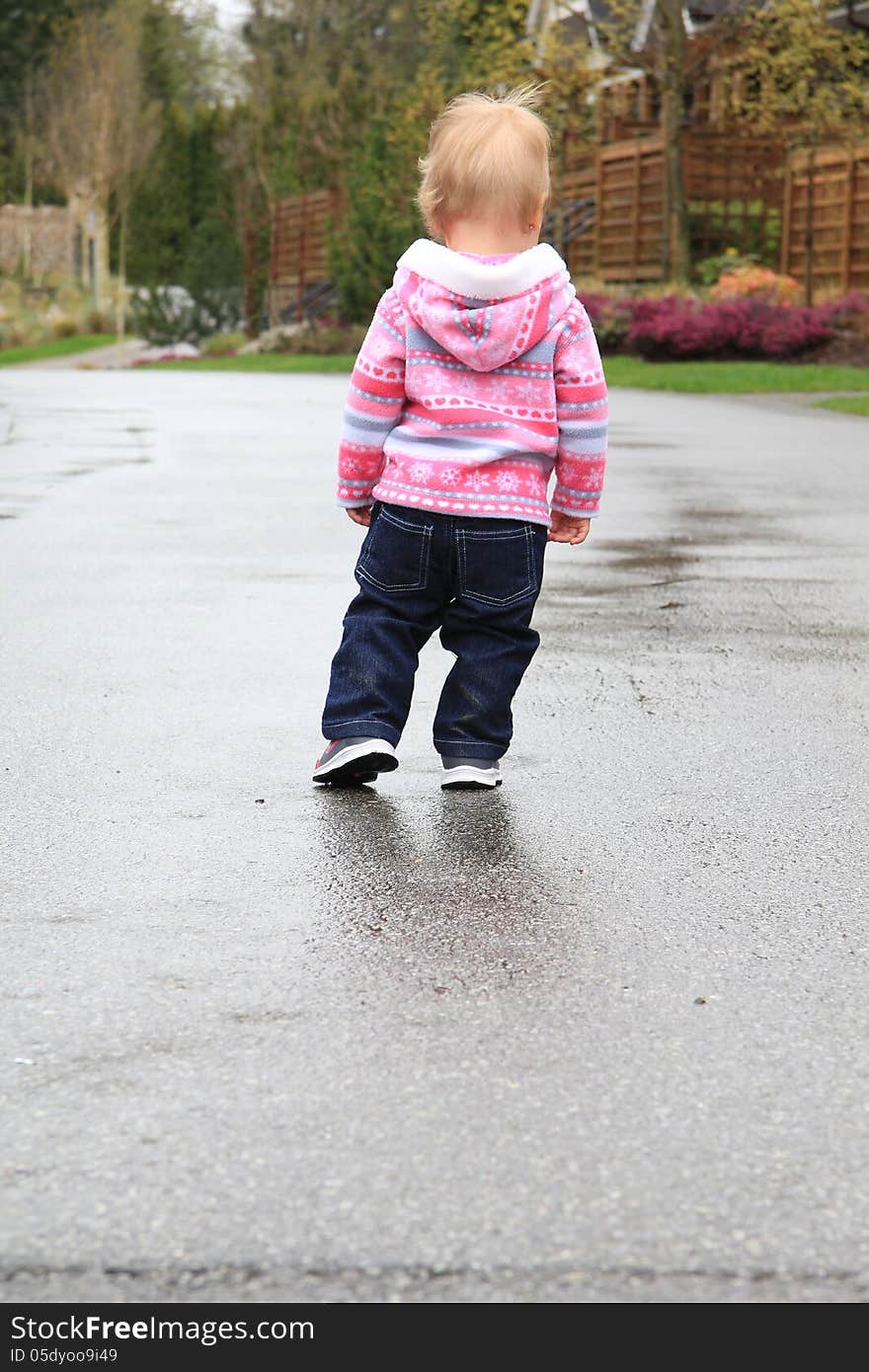 One year old little girl playing in a water puddle. One year old little girl playing in a water puddle.