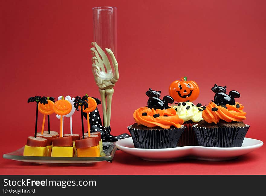 Happy Halloween party food with skeleton hand glass on red background.