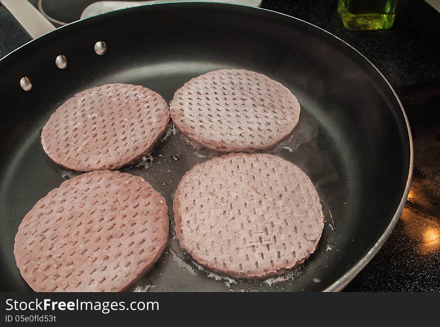 Four hamburgers on frying pan