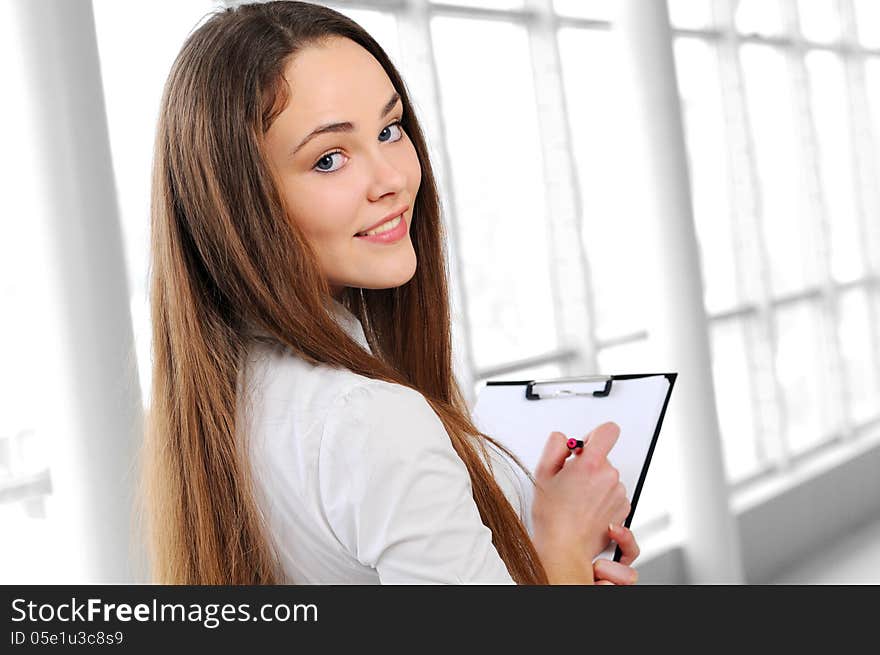 Young business girl with a folder in hands at office