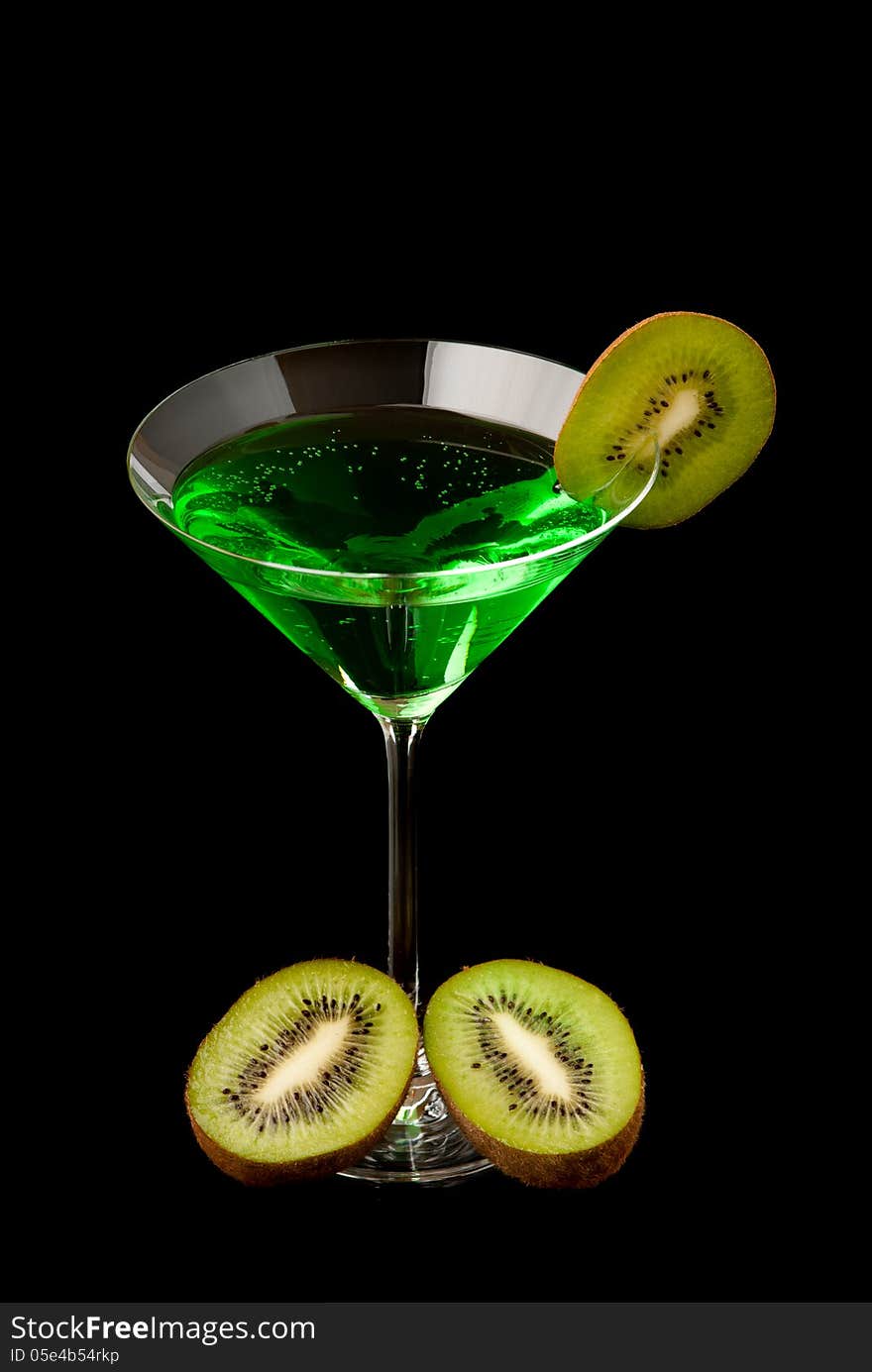 Glass filed with green beverage and a pieces of kiwi. Black background. Studio shot.