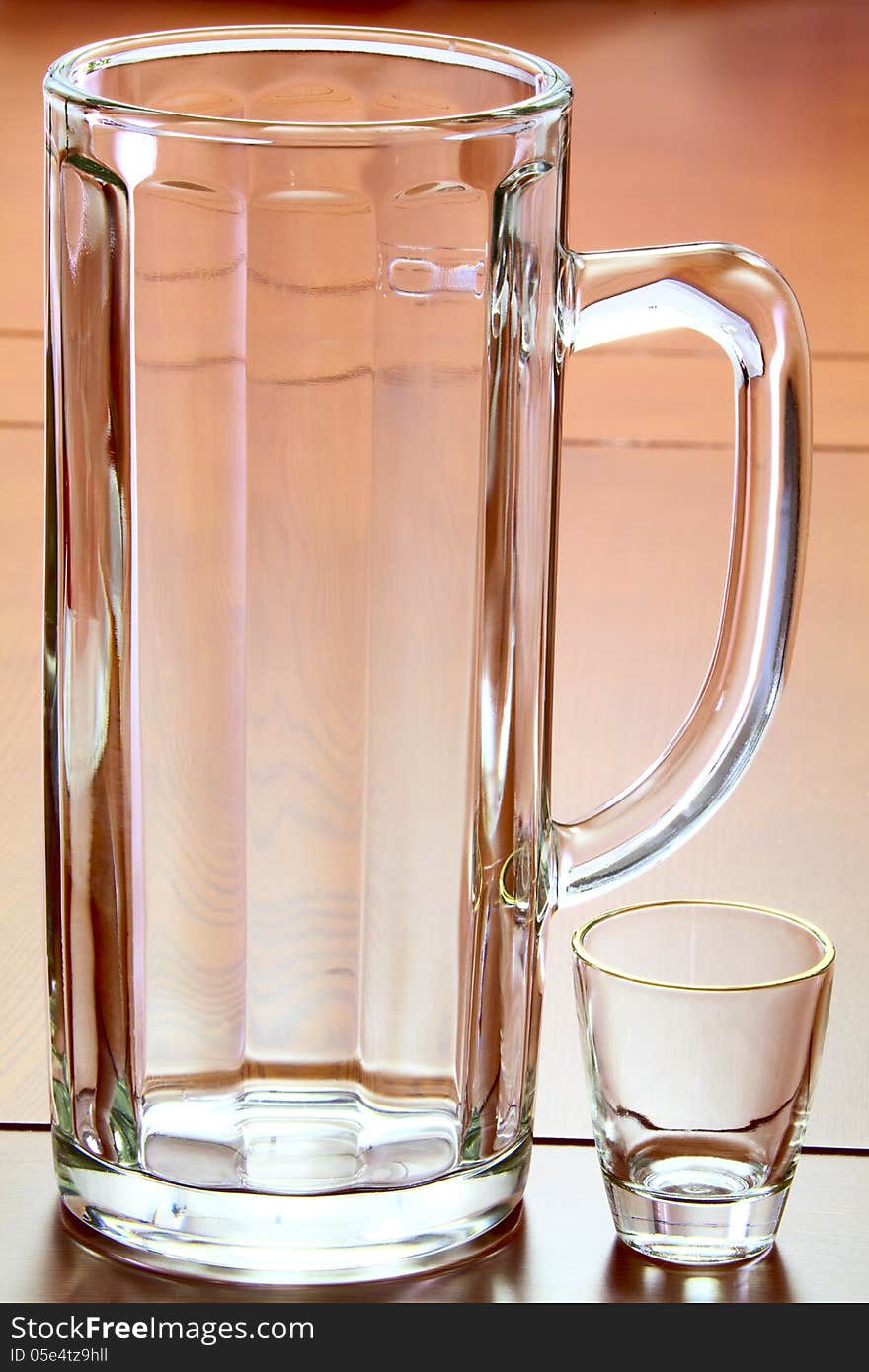 On the table an empty beer mug and a small glass for liquor. On the table an empty beer mug and a small glass for liquor