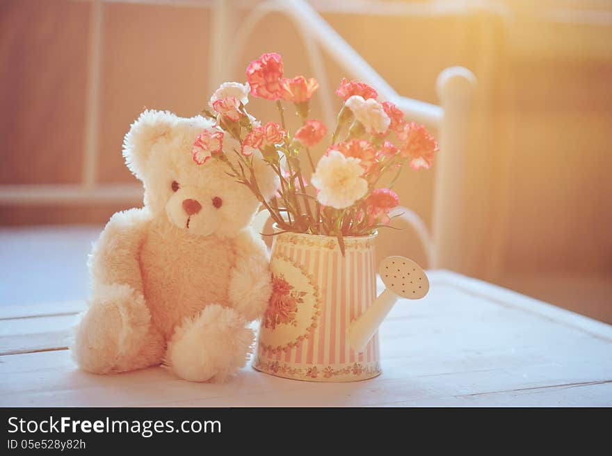 Still life with teddy bear and pink flowers in the watering can with soft back light. Still life with teddy bear and pink flowers in the watering can with soft back light