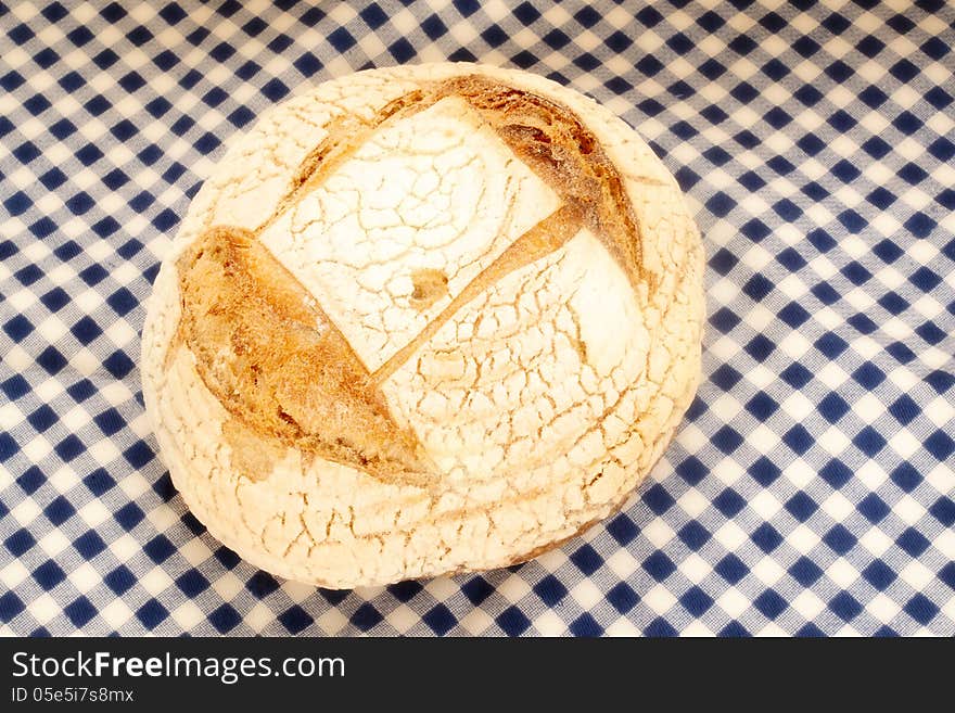 Rustic organic bread made ??by hand on a blue checkered tablecloth