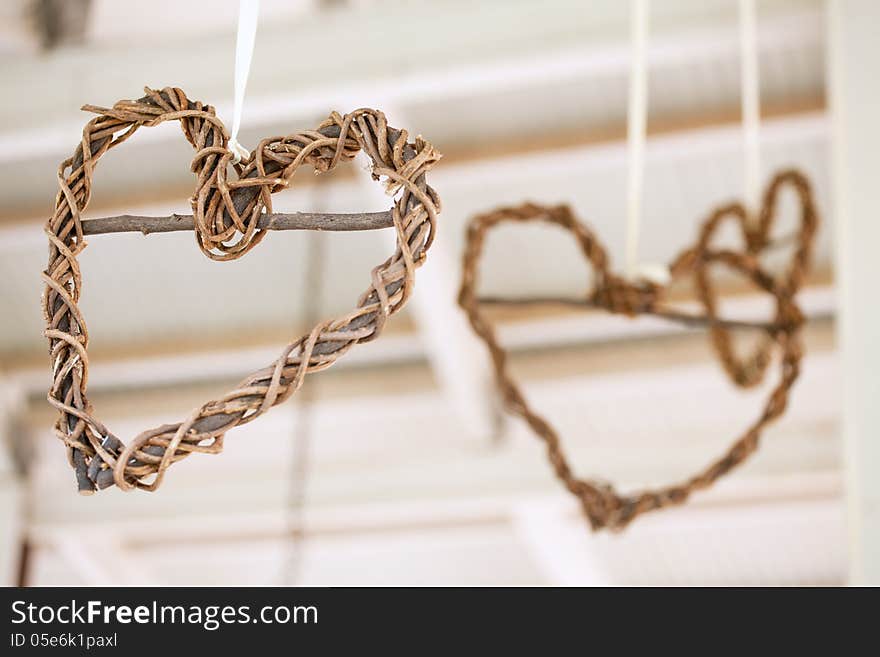 Wooden weaved hearts hanging off roof trusses at wedding, select