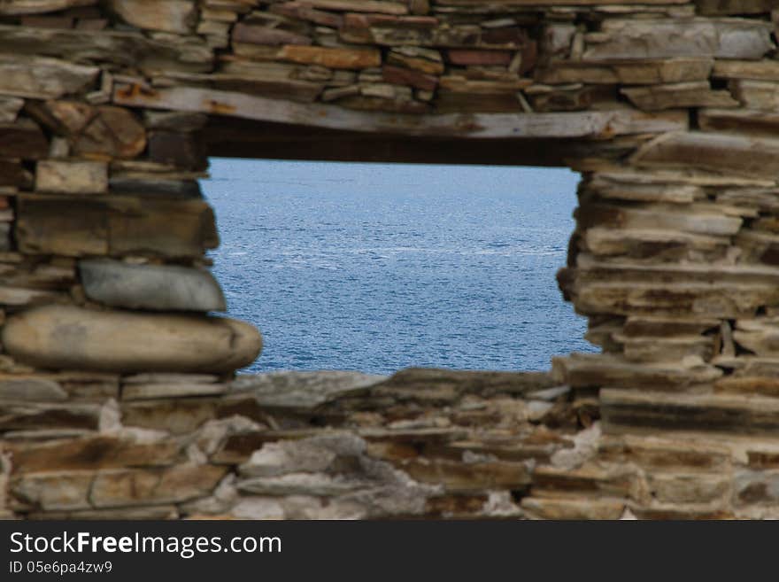 Window from blue sea stone wall blurred ruined house. Window from blue sea stone wall blurred ruined house