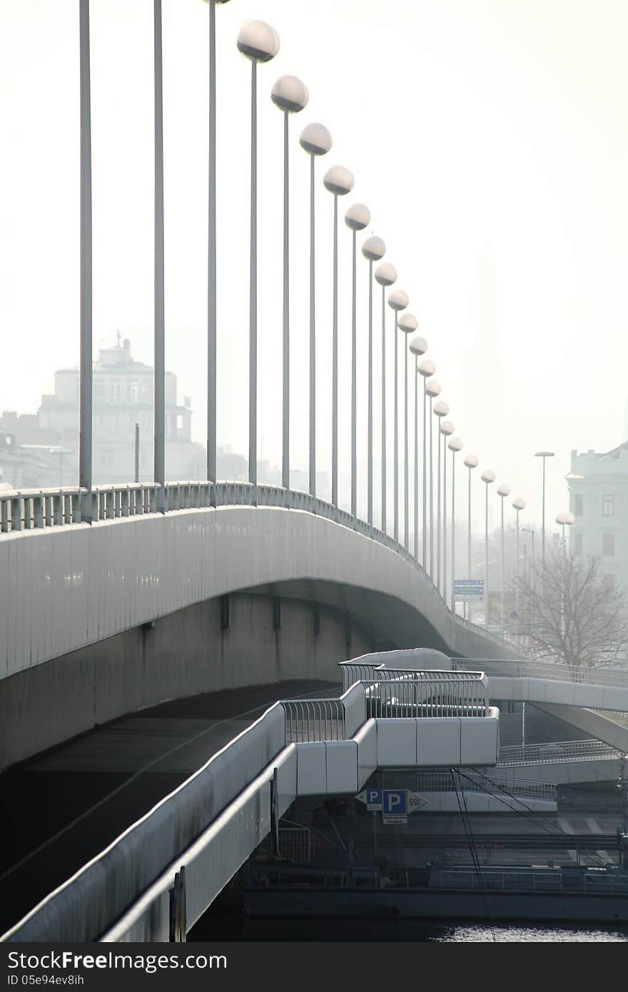 A bridge crossing the danube-river in Vienna Austria, seamed with high poles bearing lantern in the form of spheres. The impression that the distance between the poles is very short is due to the using of a lens with long focal length. A bridge crossing the danube-river in Vienna Austria, seamed with high poles bearing lantern in the form of spheres. The impression that the distance between the poles is very short is due to the using of a lens with long focal length.