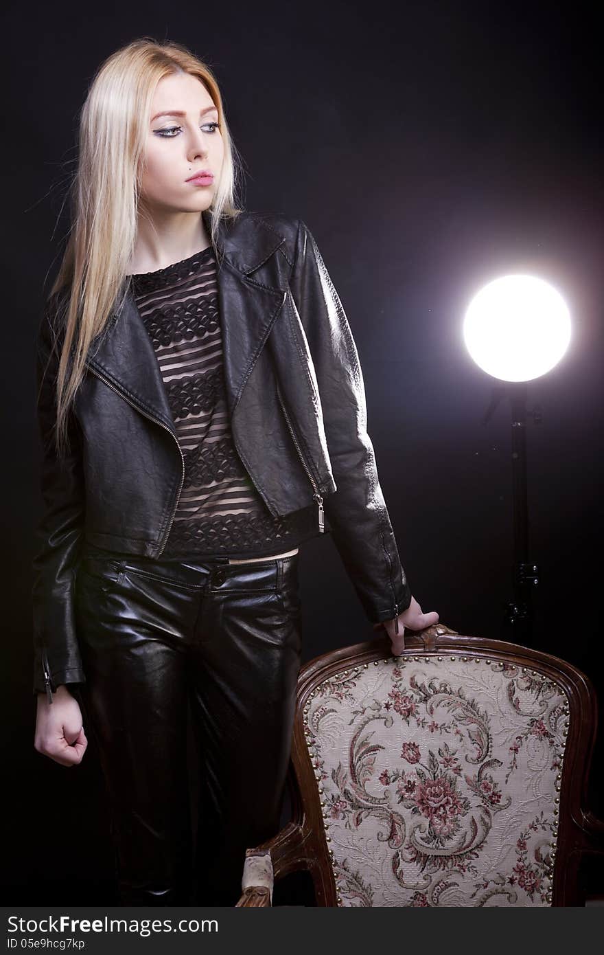 blonde next to a vintage chair on a black background studio shot. blonde next to a vintage chair on a black background studio shot