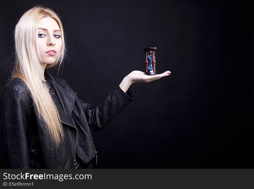 Glamour girl with a sand clock in hand on black background