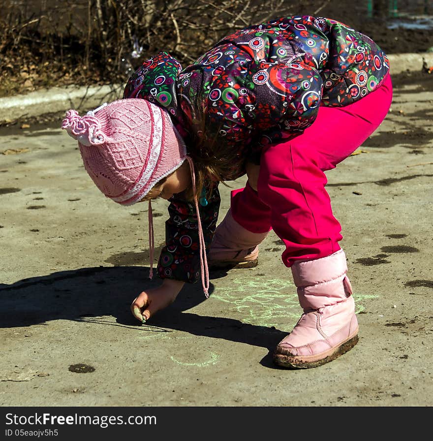 Girl drawing with chalk on asphalt. Girl drawing with chalk on asphalt