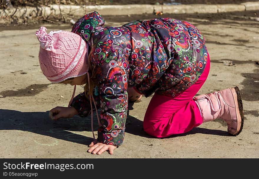 Girl drawing with chalk on asphalt. Girl drawing with chalk on asphalt