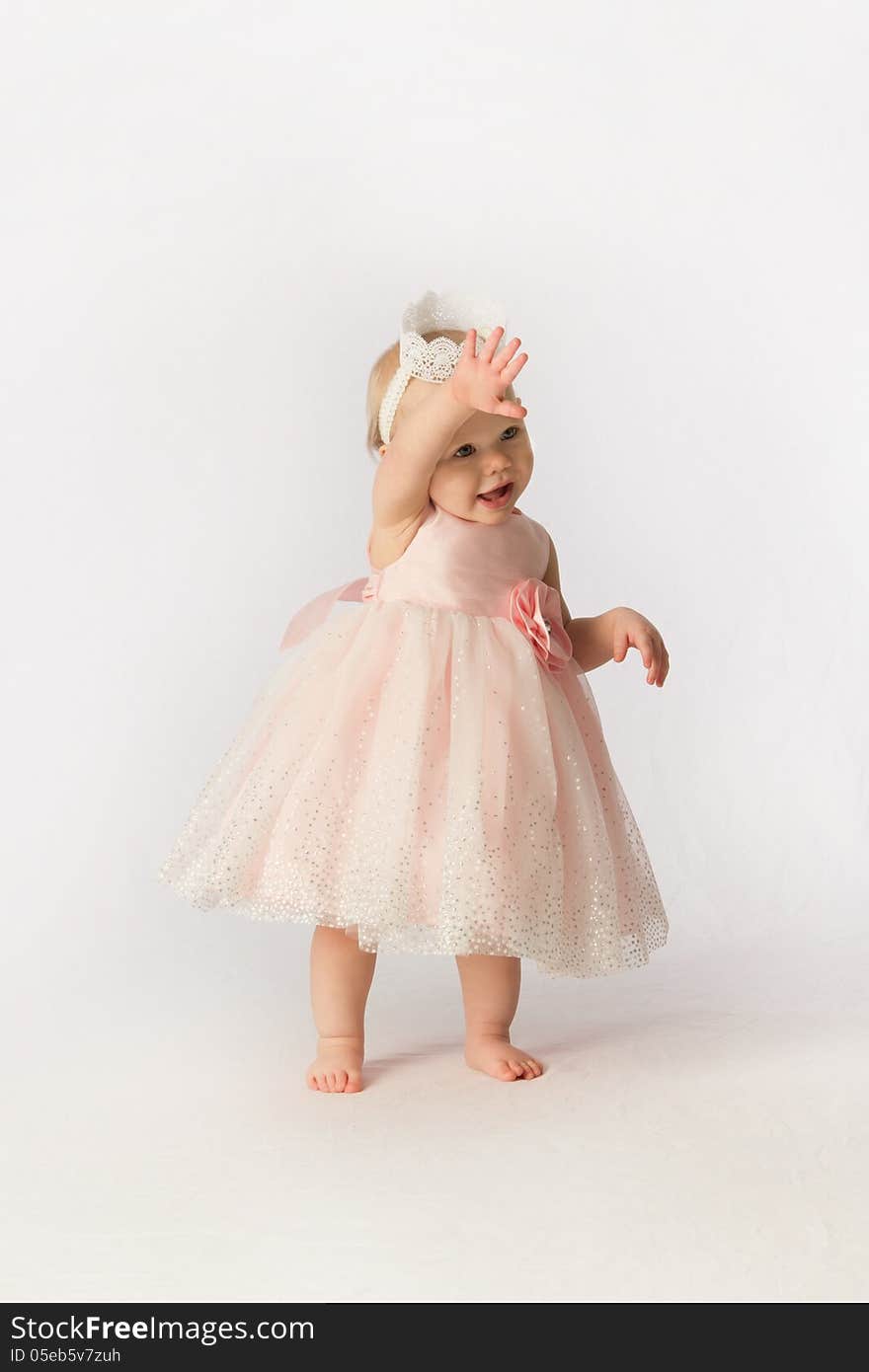 A little girl in a frilly dress and tiara waving on a white background. A little girl in a frilly dress and tiara waving on a white background