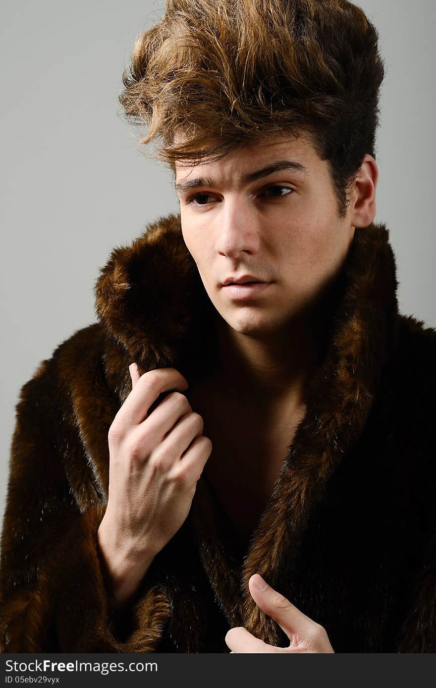 Attractive young man wearing fur coat with modern hairstyle