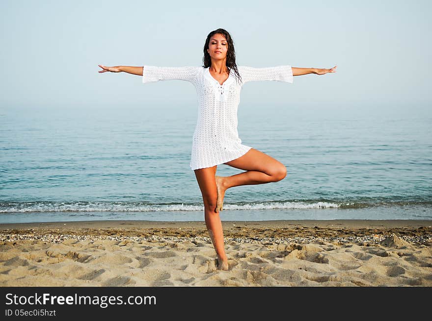 Portrait of a pretty woman doing yoga on the beach