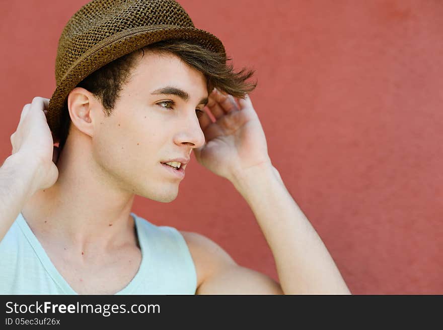 Portrait of attractive young man in urban background wearing a sun hat