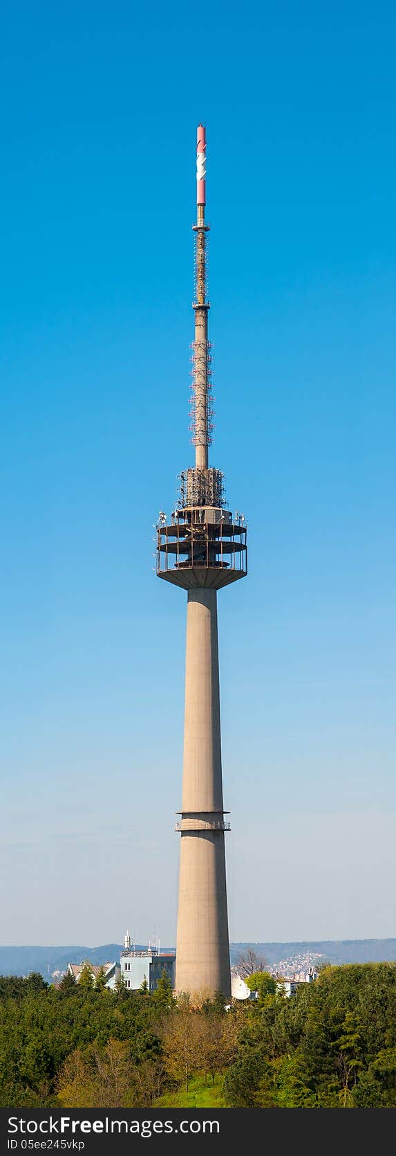 Vertical photo of a huge TV antenna tower, against blue sky. It is used for radio and TV broadcasting.