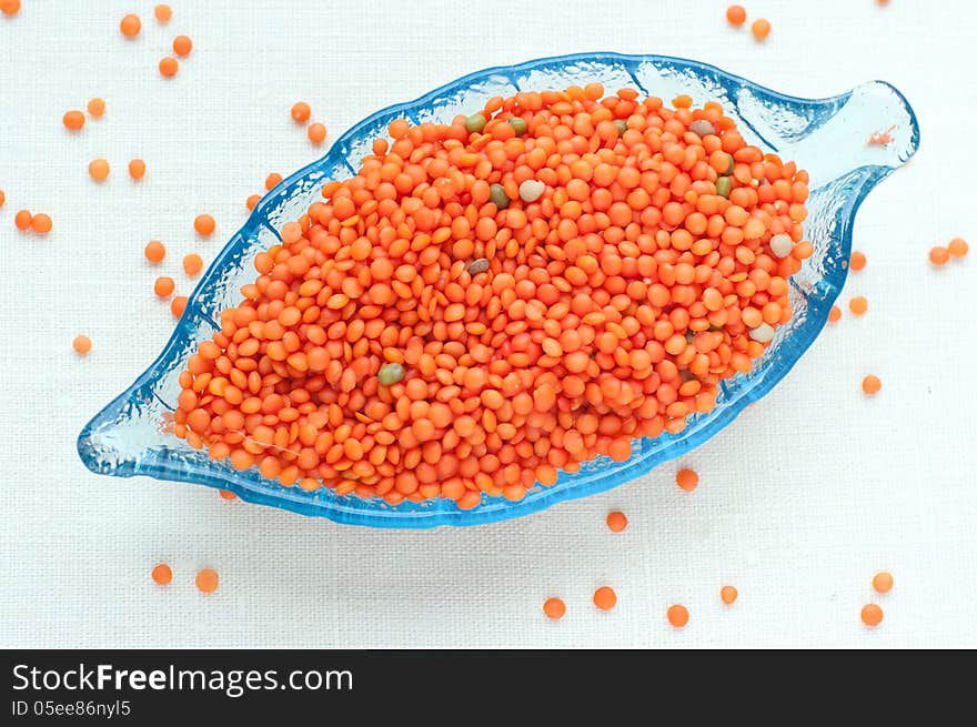 Upper view on raw red lentils in a leaf-shaped glass plate. Upper view on raw red lentils in a leaf-shaped glass plate