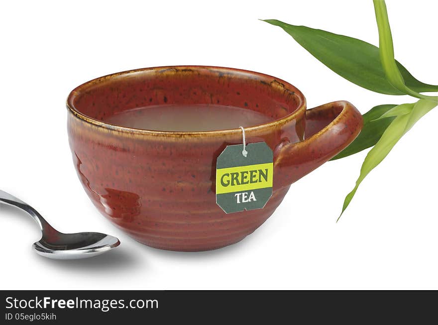 Green tea in a red tea cup pictured with bamboo and a spoon.