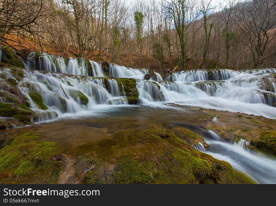 Beautiful pristine waterfalls and white water river in the mountains in early spring