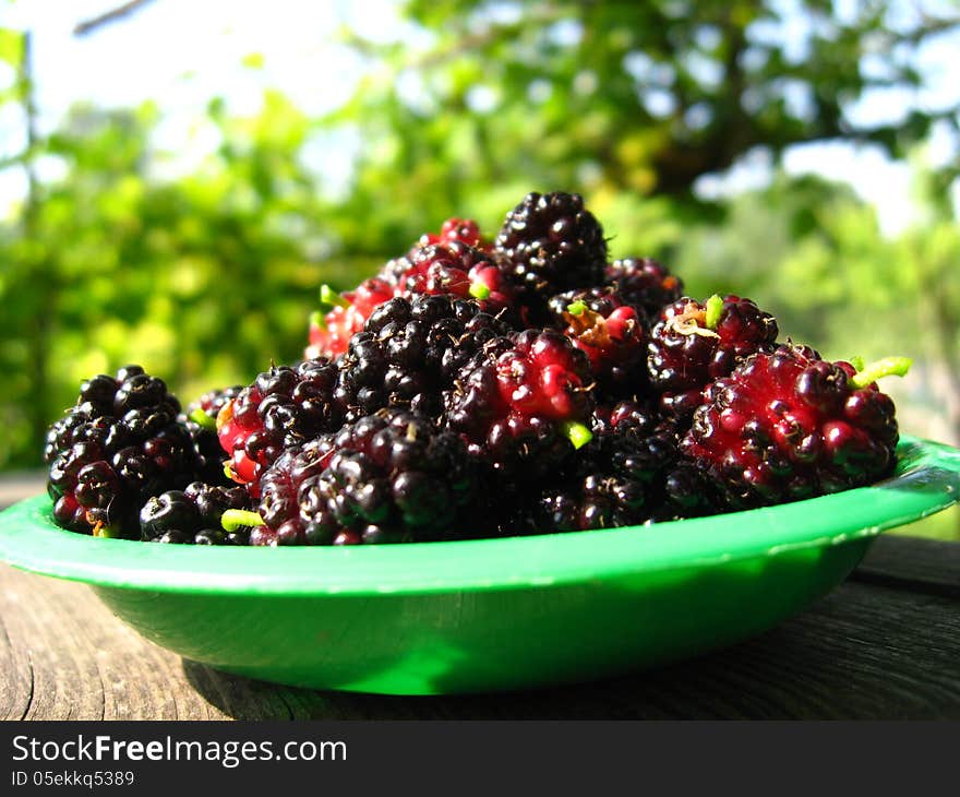 Image of ripe dark berries of mulberry on a plate