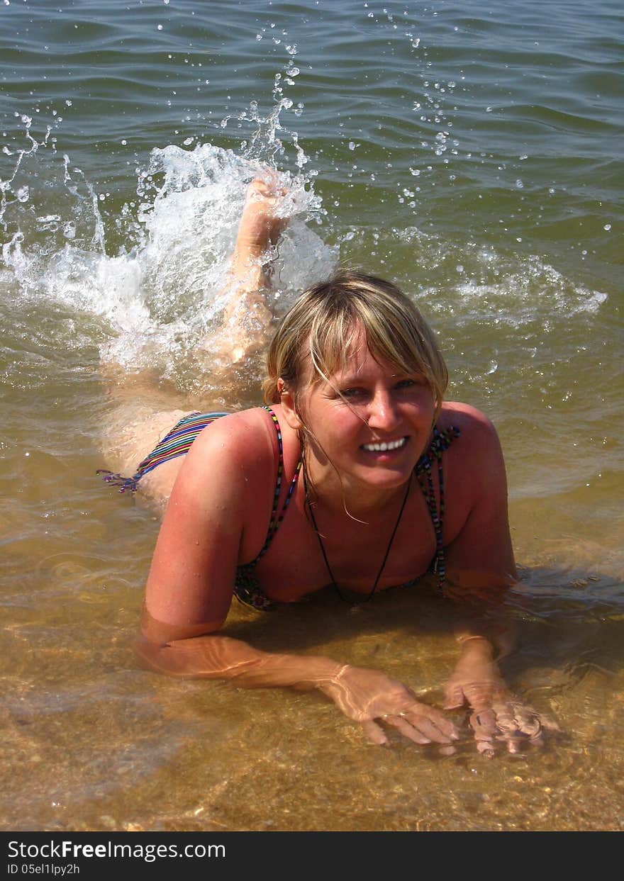 The girl splashing in the sea laying on sand