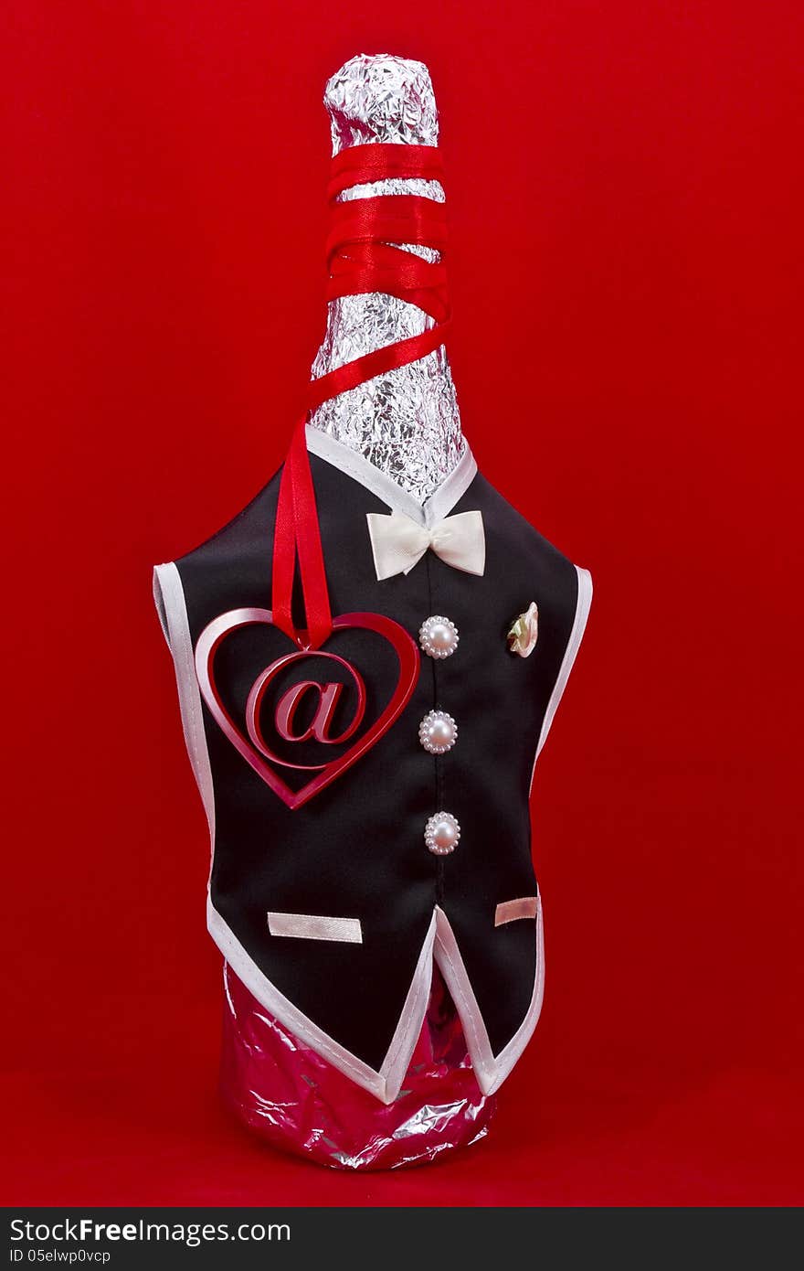 Internet dating concept shot.At symbol inside of a red heart shape with a bottle of champagne dressed in black man suit on a red background. Internet dating concept shot.At symbol inside of a red heart shape with a bottle of champagne dressed in black man suit on a red background.