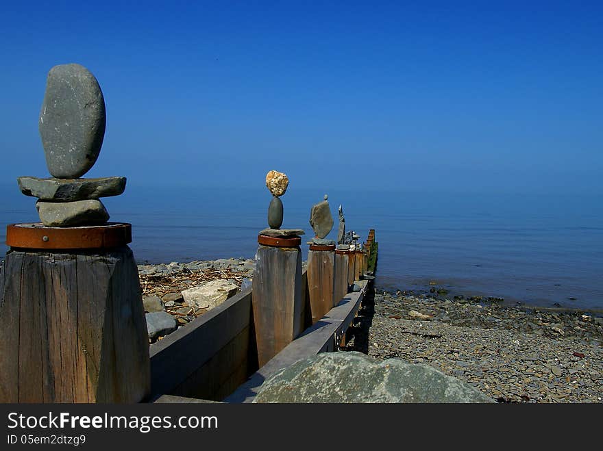 Stones balanced on groynes at Aberaeron beach in Whales UK with calm sea blue sky. Stones balanced on groynes at Aberaeron beach in Whales UK with calm sea blue sky.