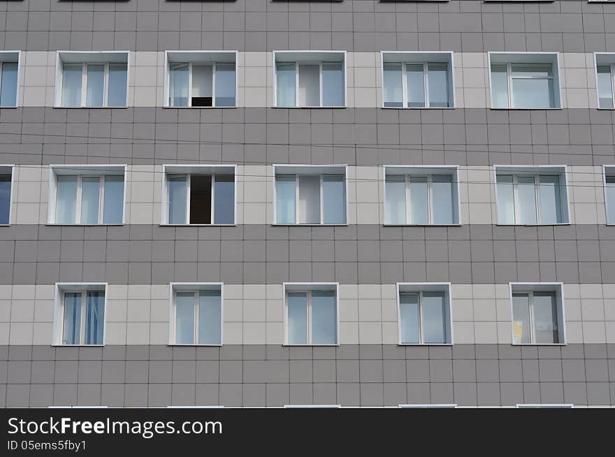 The gray wall of a building with windows.