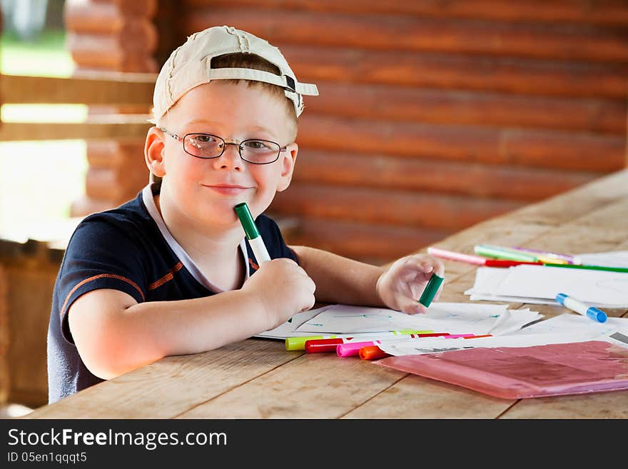 Cute boy drawing in wooden gazebo