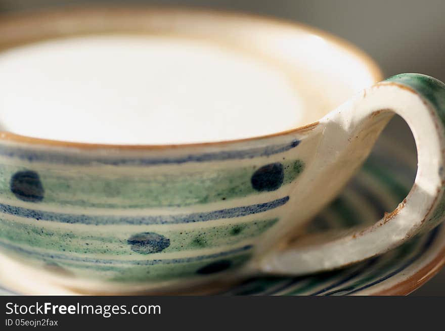 A whimsical cup and saucer containing a frothy cafe latte. A whimsical cup and saucer containing a frothy cafe latte.