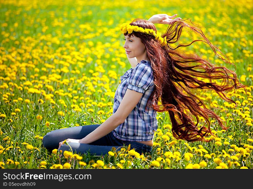 The beautiful girl are sitting on the glade of dandelions. The beautiful girl are sitting on the glade of dandelions