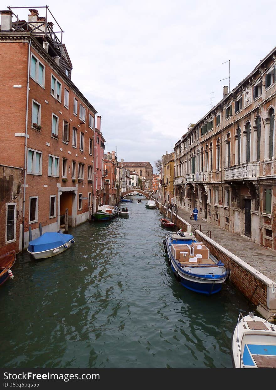 Venice - a view of a small canal with boats and the town street